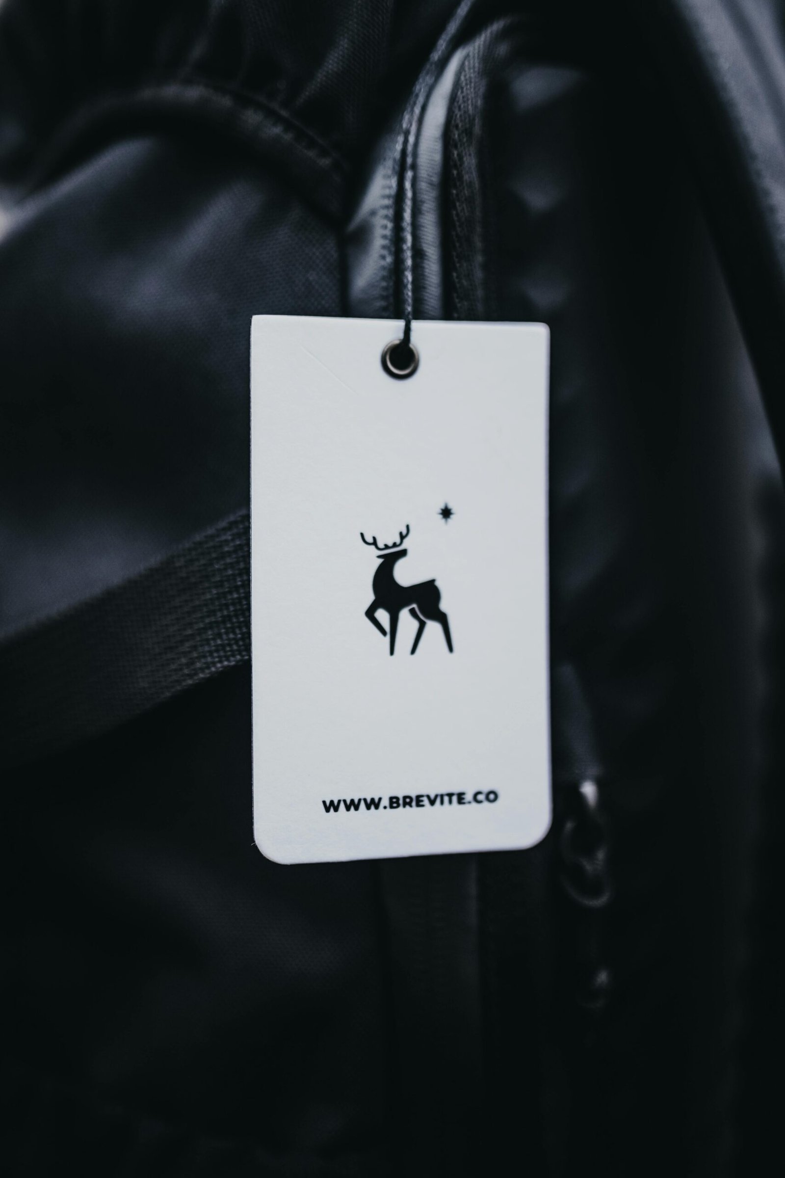 A close-up view of a branding tag on a sleek black backpack, showcasing minimalistic design.