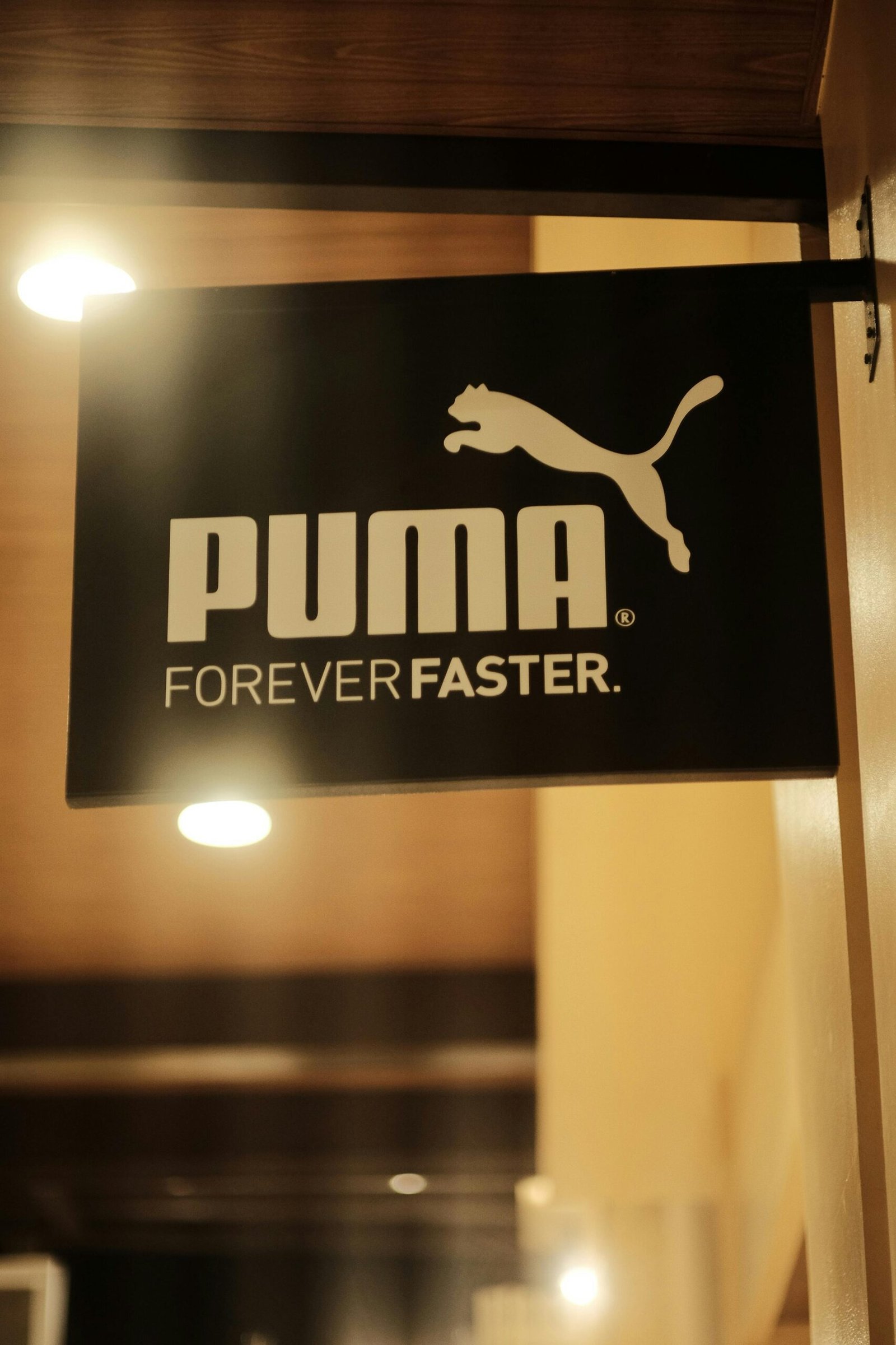 A glowing Puma store sign with the slogan 'Forever Faster' at night.