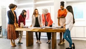 A diverse group of women collaborating on a project in a modern office setting.